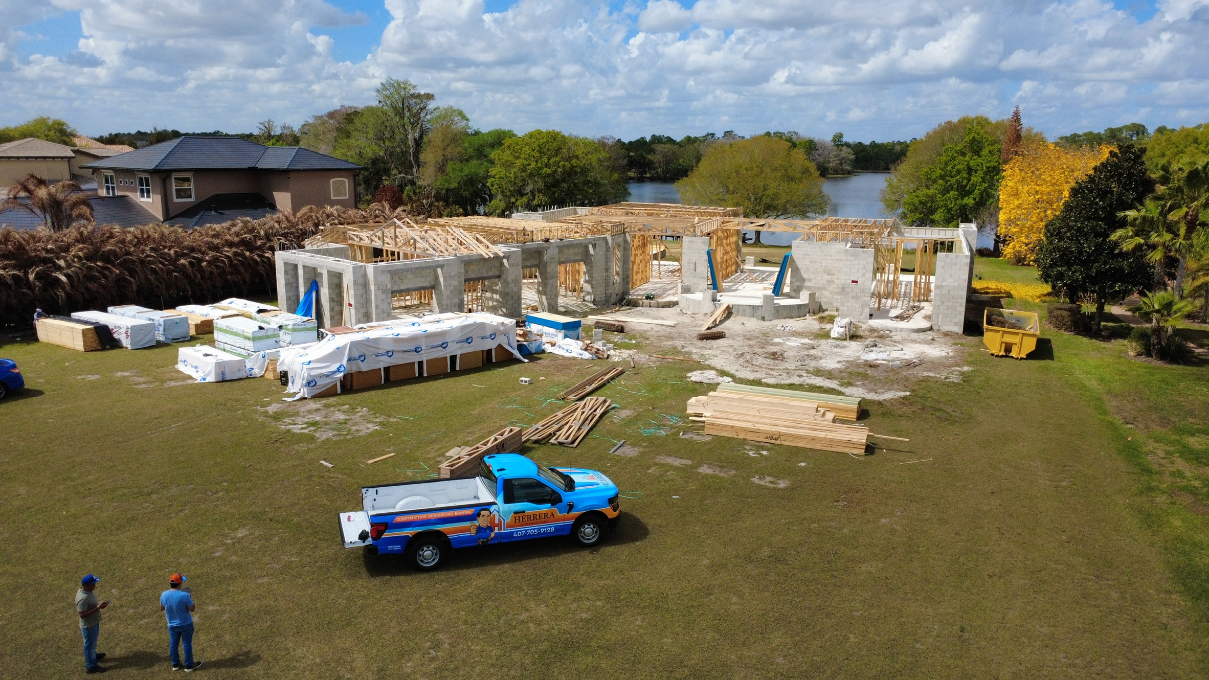Lakefront new-construction home under framing with Herrera Contractors truck on site